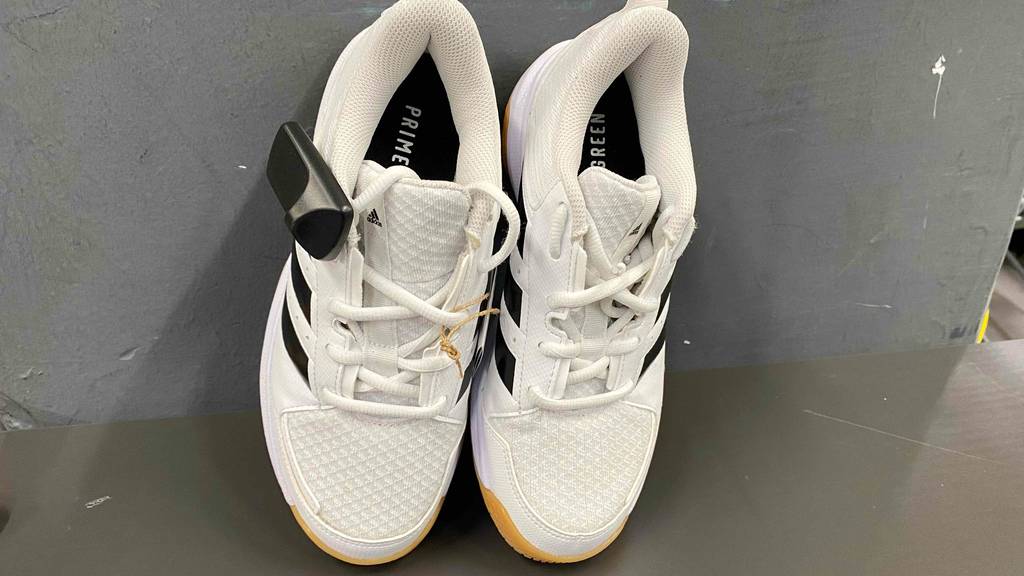 Ein Paar getestete Handballschuhe für Damen lehnen mit der Sohle an einer Wand.