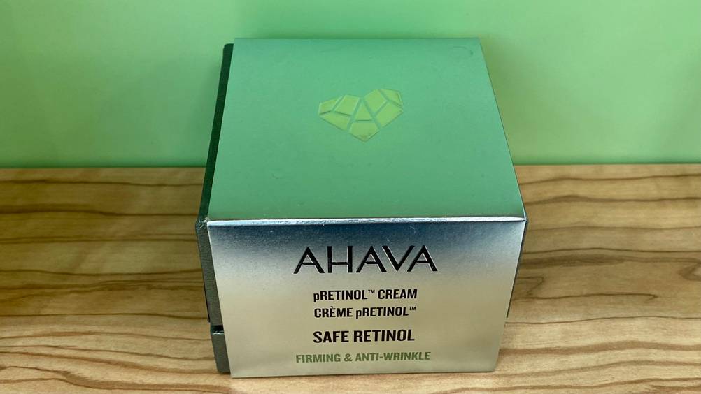 Eine getestete Retinol-Creme in Originalverpackung vor einer grünen Wand.