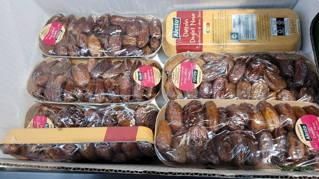 Mehrere Packungen getesteter getrocknete Datteln sind in einem Karton einsortiert.
