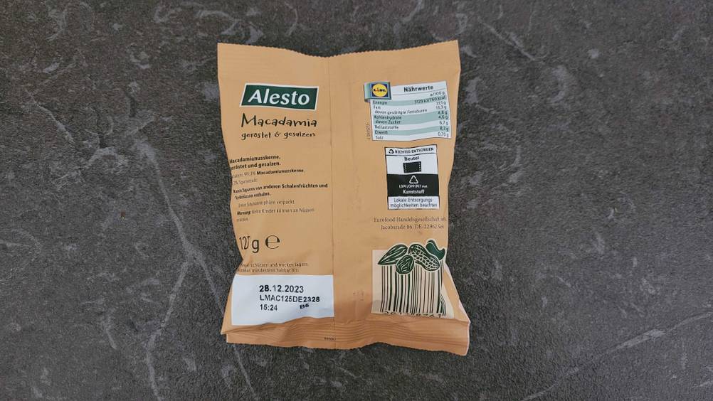 Die Rückseite einer Packung getesteter Macadamia-Nüsse auf einer dunklen Oberfläche.
