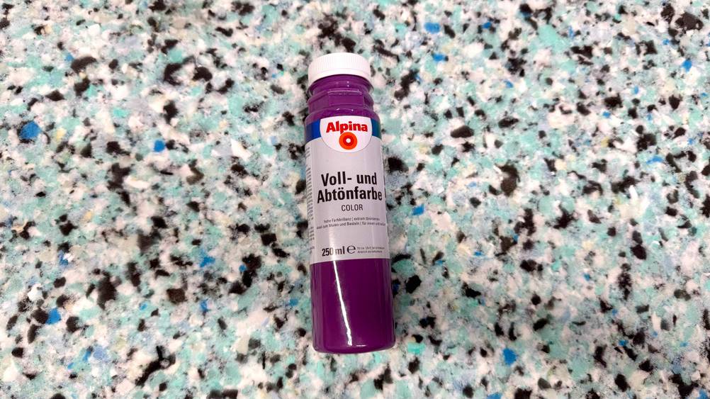 Eine Flasche der getesteten Abtönfarbe mit 250 ml Inhalt liegt auf einem Boden.