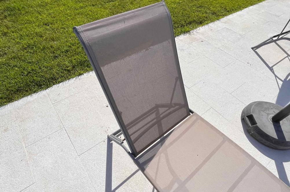Im Test: Eine Aluminium-Sonnenliege schräg von der Seite auf einem Fließenboden.