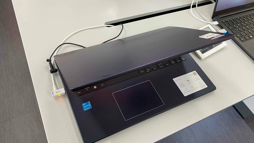 Günstiger-Laptop-Test: halb zugeklappter, gesicherter Laptop steht in einem Geschäft neben anderen Geräten.