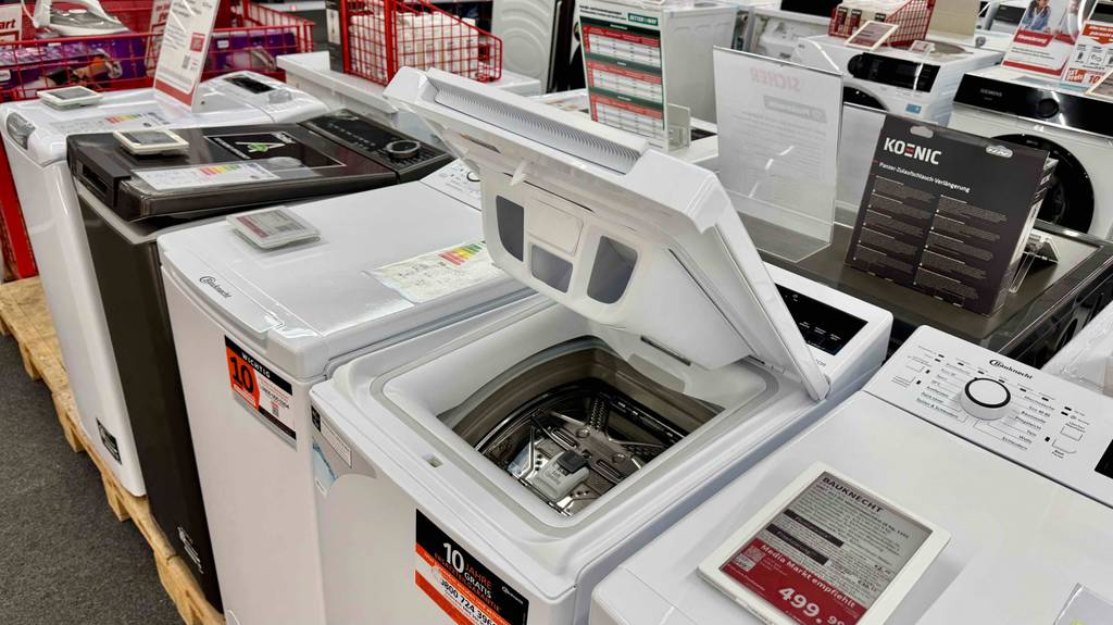 Der getestete Bauknecht-Toplader steht mit geöffnetem Deckel zwischen weiteren Topladern im Elektrofachmarkt.
