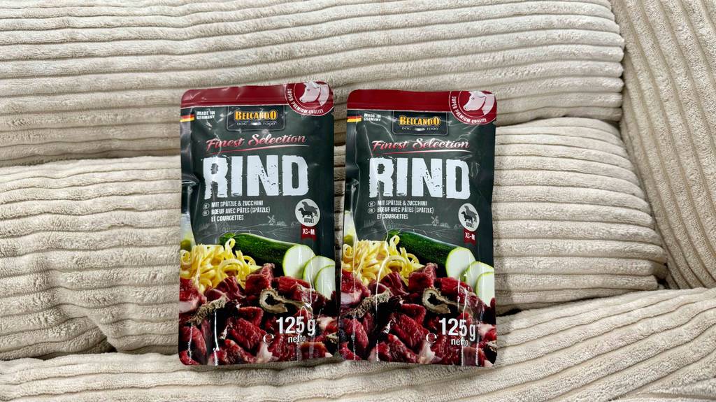 Belcando-Hundefutter im Test: zwei Belcando-Hundefutter in der Geschmacksrichtung Rind sind auf einer beigen Sitzfläche platziert.