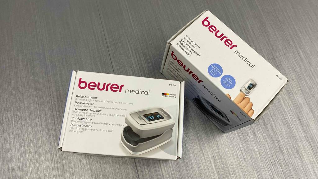 Pulsoximeter getestet: Zwei verpackte Geräte nebeneinander auf einem grauen Boden.