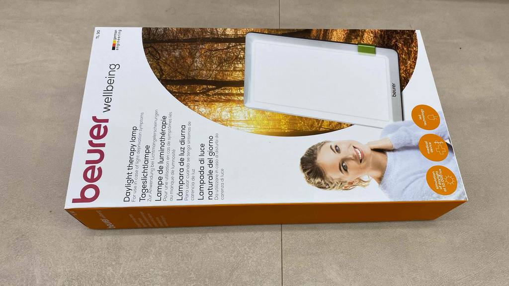 Beurer-Tageslichtlampe getestet: Eine verpackte Lampe liegt horizontal auf einem Fließenboden.