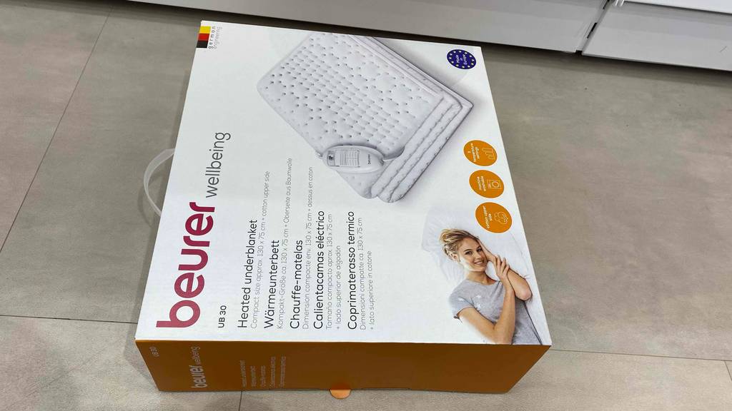 Wärmeunterbett getestet: Ein verpacktes Wärmeunterbett liegt auf einem hellen Boden.