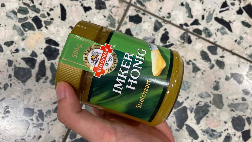Bihophar Honig im Test: Eine Hand hält ein Glas Honig vor Fließen
