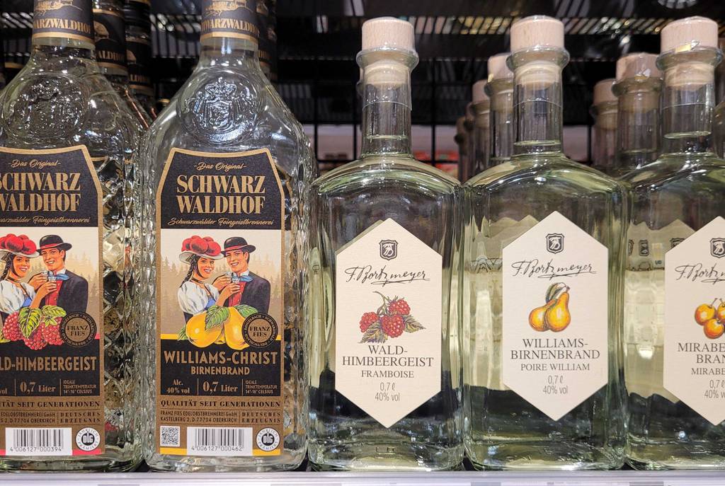 Der getestete Himbeerlikör steht innerhalb einer transparenten Flasche mit Wald-Himbeergeist neben weiteren Bränden auf einem Verkaufsregal.