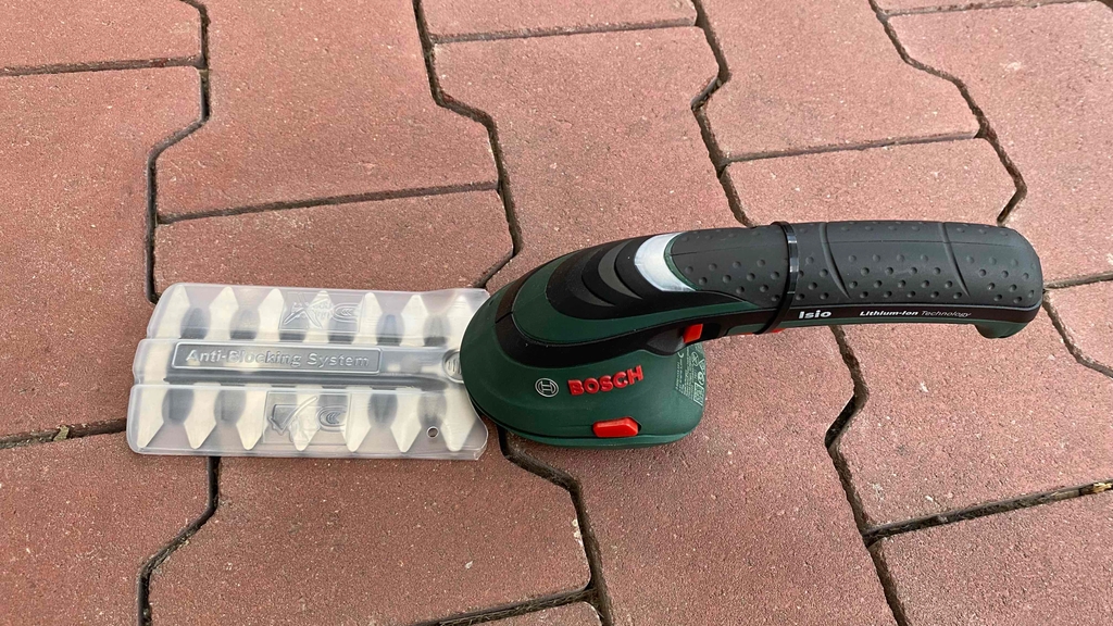 Akku-Grasschere im Test: Akku-Grasschere steht auf einem roten Steinboden.