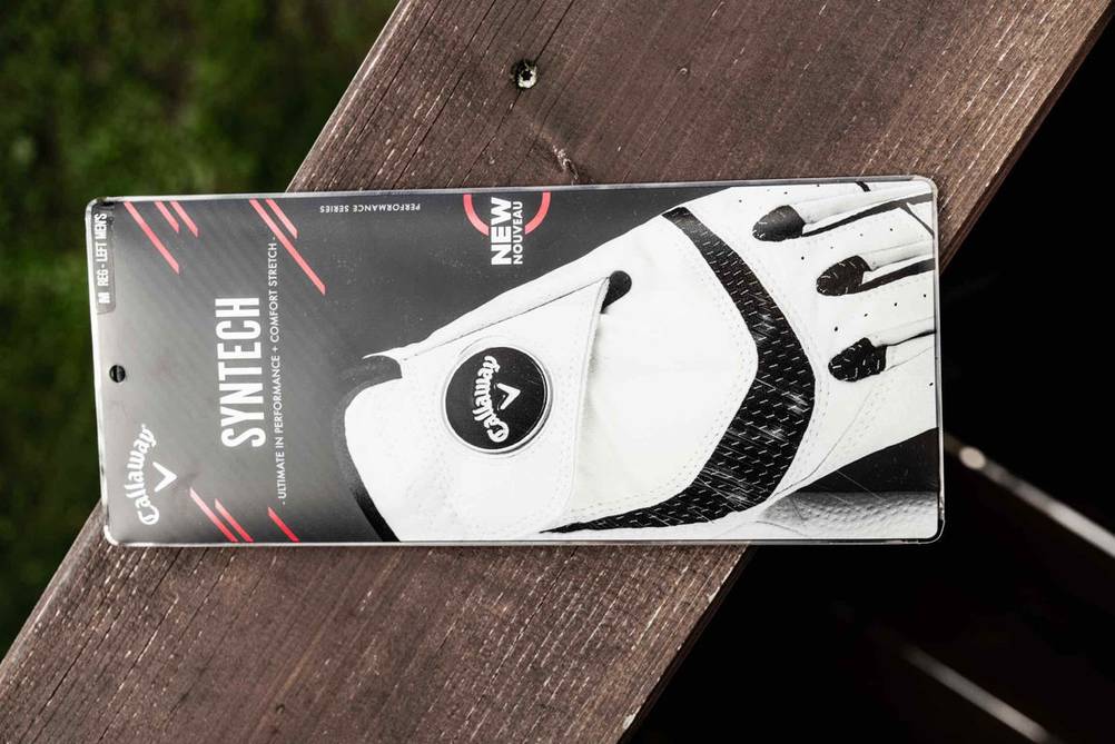 Golfhandschuh getestet: die Verpackung eines weißen Golfhandschuhs auf einer Holzfläche abgelegt.