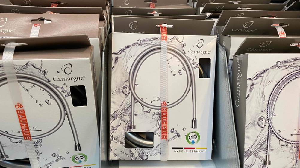 Mehrere getestete Brauseschläuche in Verpackung hängen im Regal.