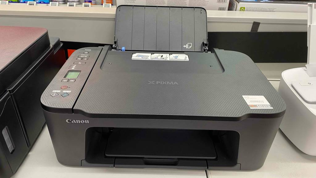 Auf einer Oberfläche steht ein getesteter Canon-Multifunktionsdrucker neben anderen Geräten.