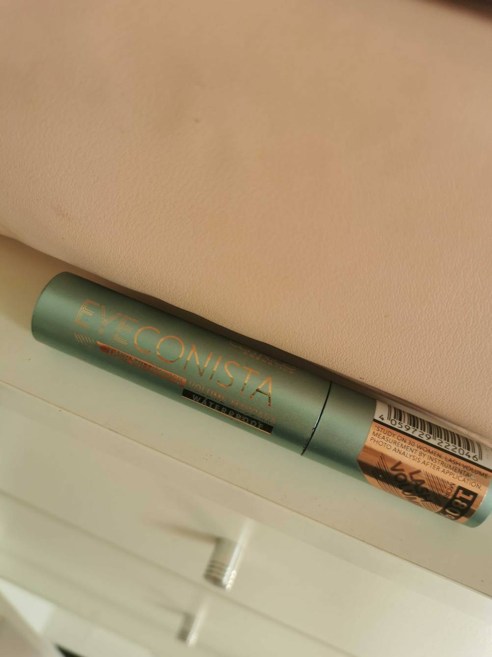 Eine Tube der getesteten wasserfesten Mascara liegt vor einer hellen Wand.