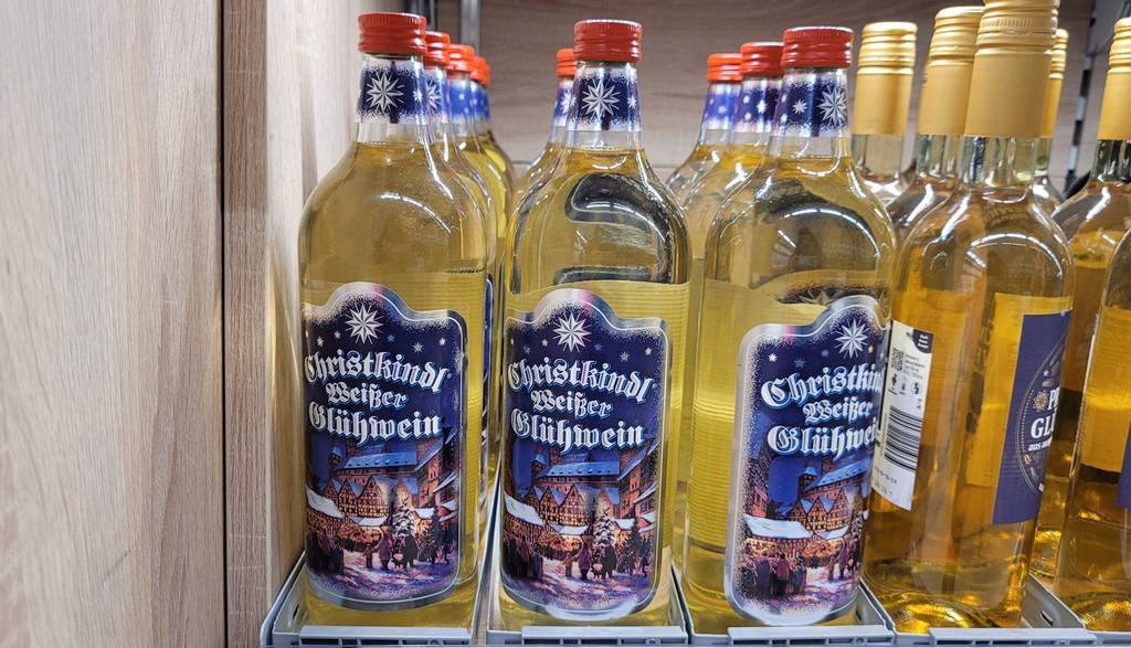 mehrere Flaschen des getesteten weißen Glühweins stehen in einem Regal.
