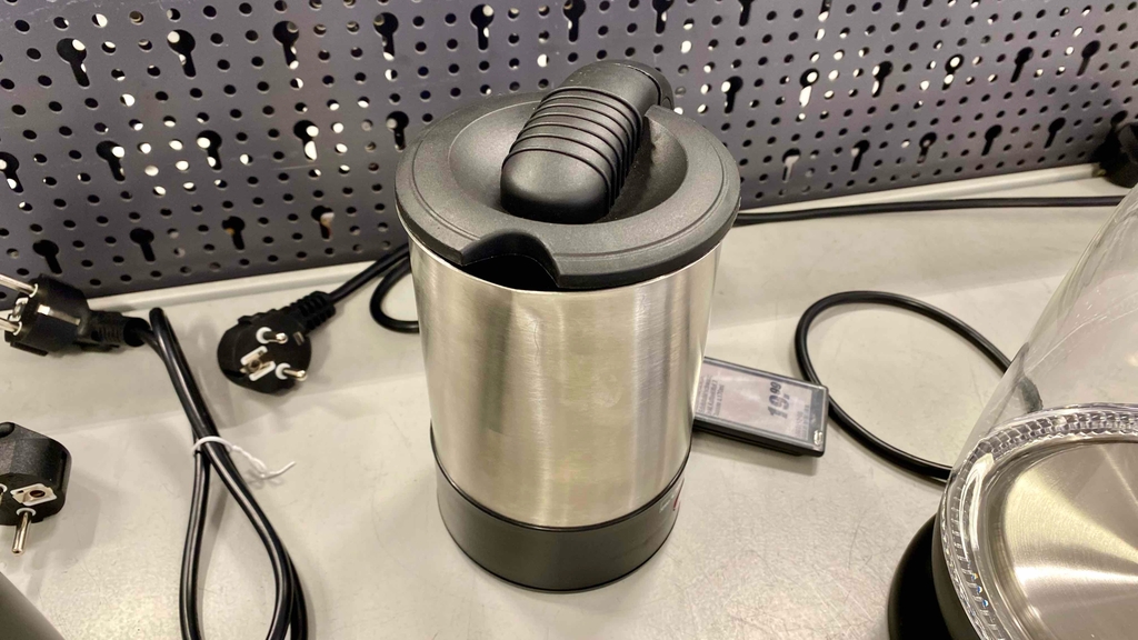 Ein getesteter Reisewasserkocher von vorne mit Ausgießer auf einer hellen Ausstellungsfläche.