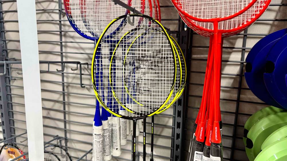 Mehrere getestete Badmintonschläger für Kinder hängen in einem Regal.