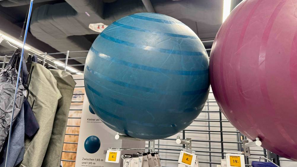 Ein blauer getesteter 65 cm Gymnastikball befindet sich in einem Geschäft neben einem rosafarbenen 65 cm Gymnastikball.