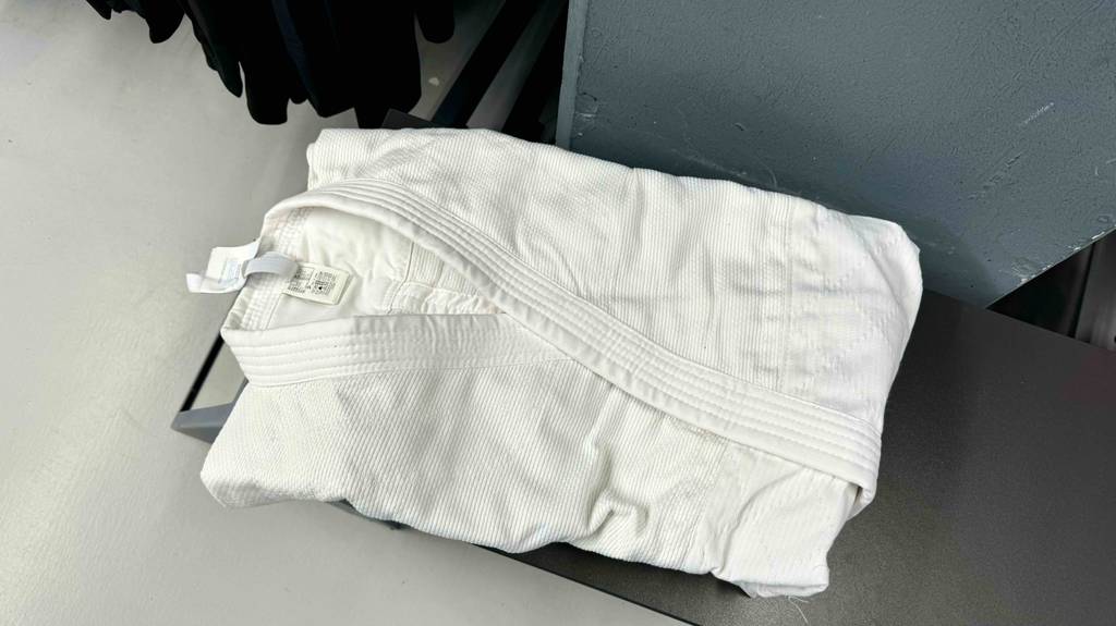 Test: ein weißer zusammengefalteter Judoanzug liegt auf einer Sitzbank.