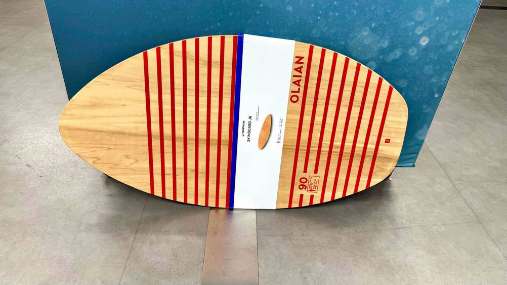 Das getestete Skimboard lehnt an einer blauen Wand.