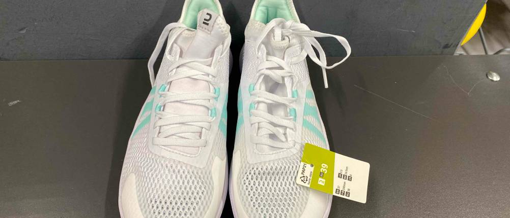 Ein Paar getestete weiße Volleyballschuhe für Damen mit Preisschild von vorne oben auf einer grauen Fläche fotografiert.