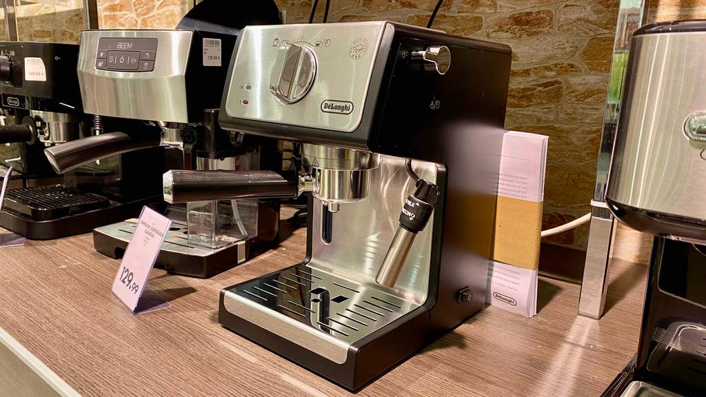 De’Longhi Siebträger-Maschine im Test: eine De’Longhi Siebträger-Maschine mit Milchaufschäumer steht in einem Geschäft neben anderen Modellen.