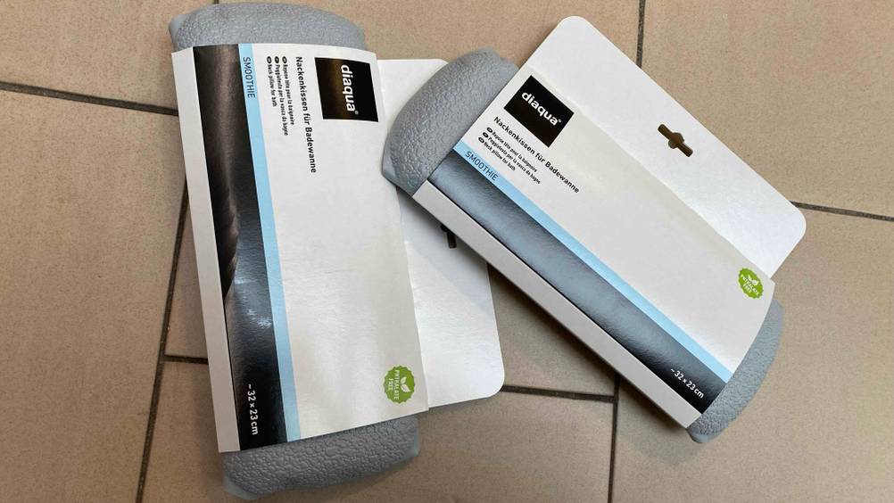 Im Test: Zwei verpackte Nackenkissen liegen leicht übereinander auf einem Fliesenboden.