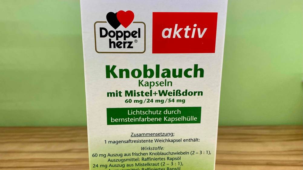Die Rückseite einer Packung der getesteten Knoblauch-Kapseln vor einer grünen Wand.
