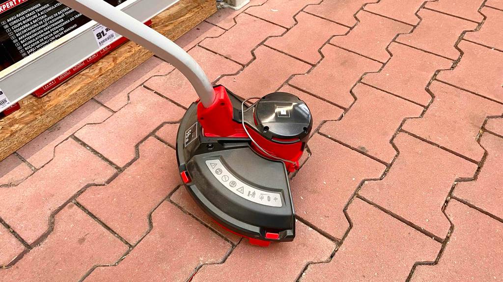 Einhell-Rasentrimmer-Test: ein Einhell-Rasentrimmer, bei welchem man den unteren Teil sieht, ist auf einem Boden platziert.