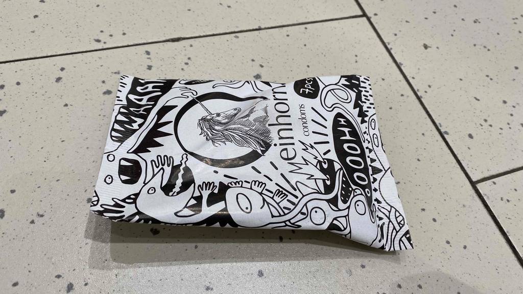 Einhorn-Komdome getestet: schwarz weiße Verpackung von Einhorn-Komdom auf einem Boden liegend.