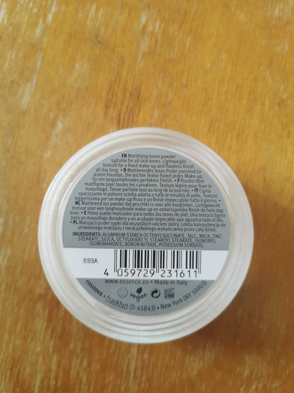 Puder getestet: Eine Dose liegt mit der Rückseite nach oben auf einer Holzfläche.