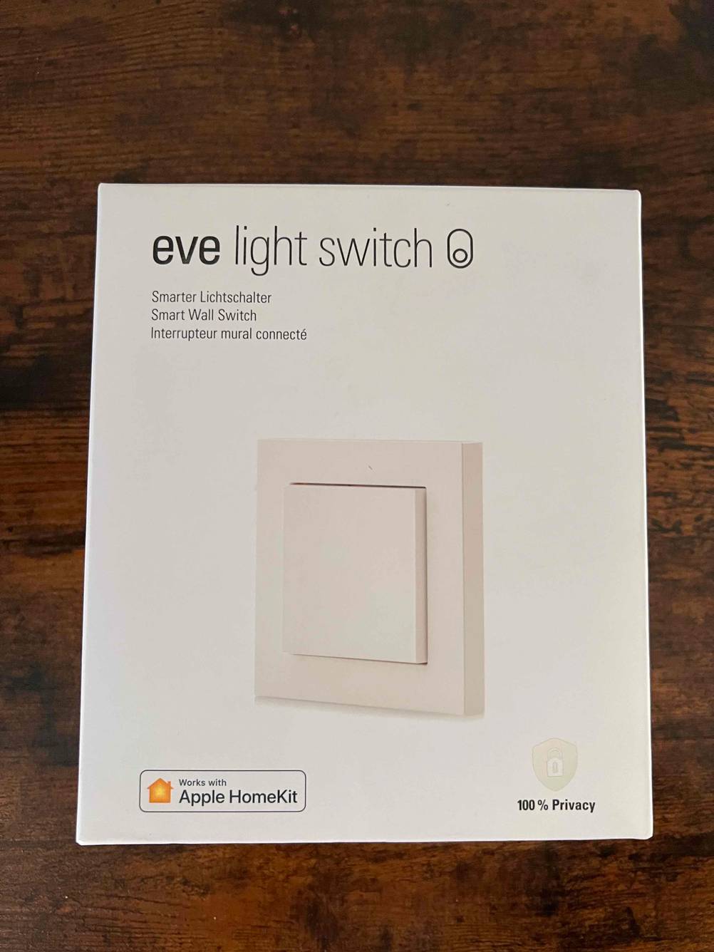 Ein getesteter Smart-Home-Lichtschalter liegt originalverpackt auf einer Holzfläche.