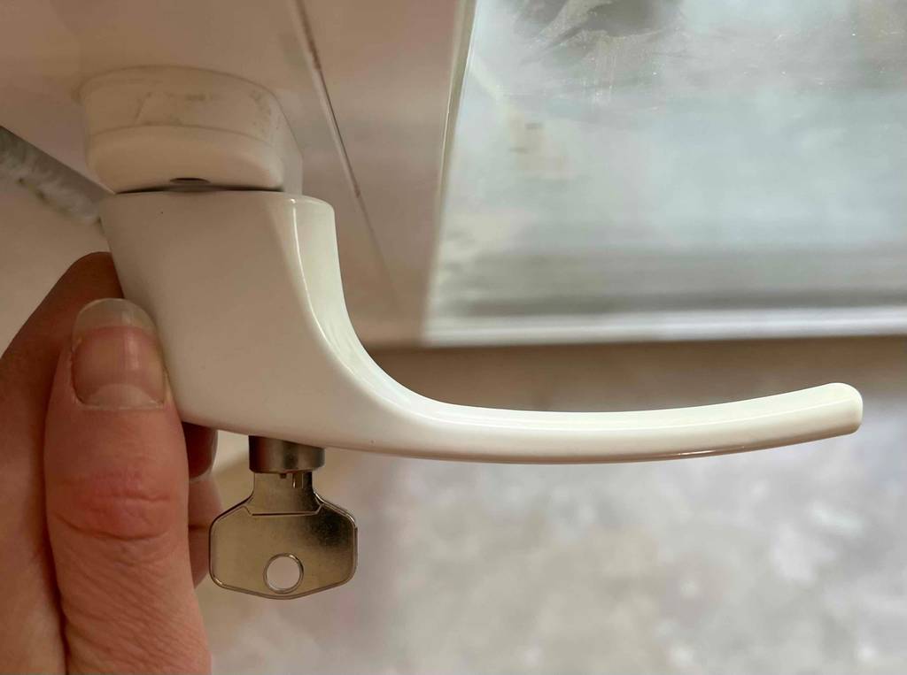 Ein getesteter abschliessbarer Fenstergriff von oben mit Schlüssel im Schloss.