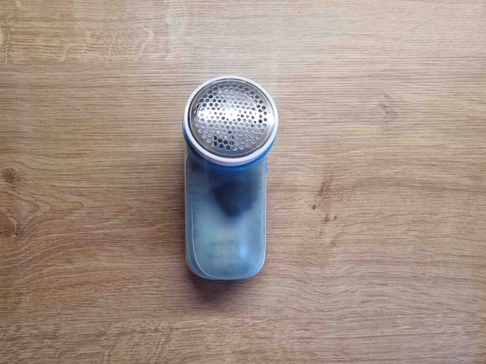 Fusselrasierer-Test: ein Fusselrasierer mit Fusseln im Behälter liegend auf einer Holzfläche.