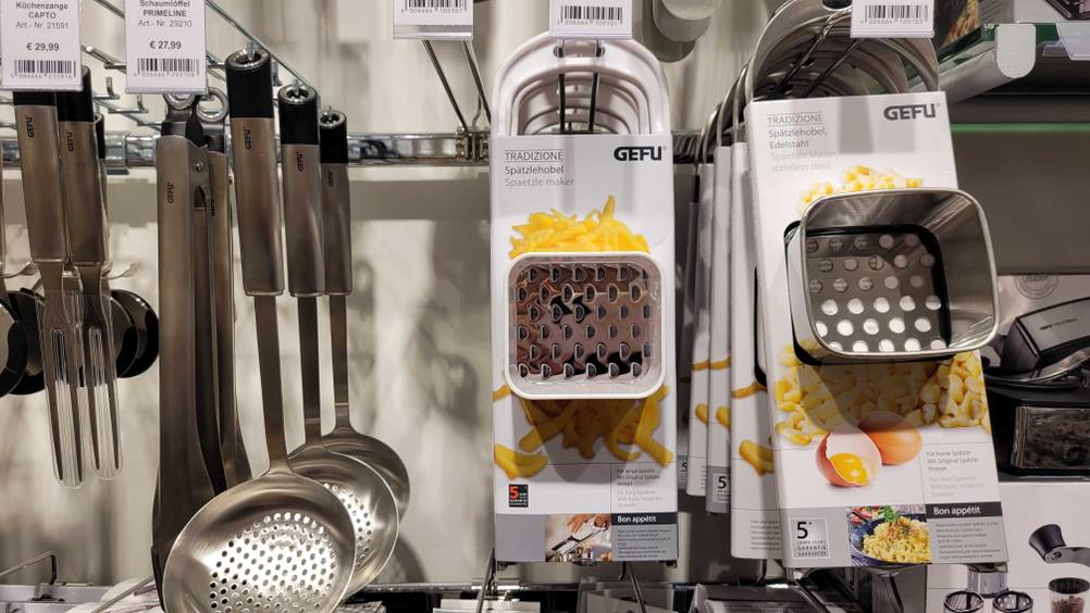 Spätzlehobel-Test: Mehrere Spätzlehobel hängen in einem Regal neben anderen Utensilien für die Küche.