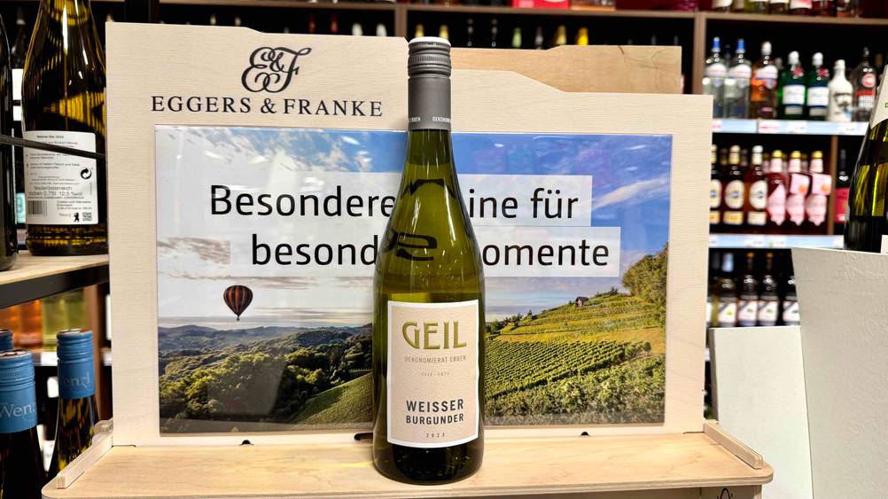 Weißburgunder-Test: Eine Flasche Wein steht vor einem Ausstellungsschild.