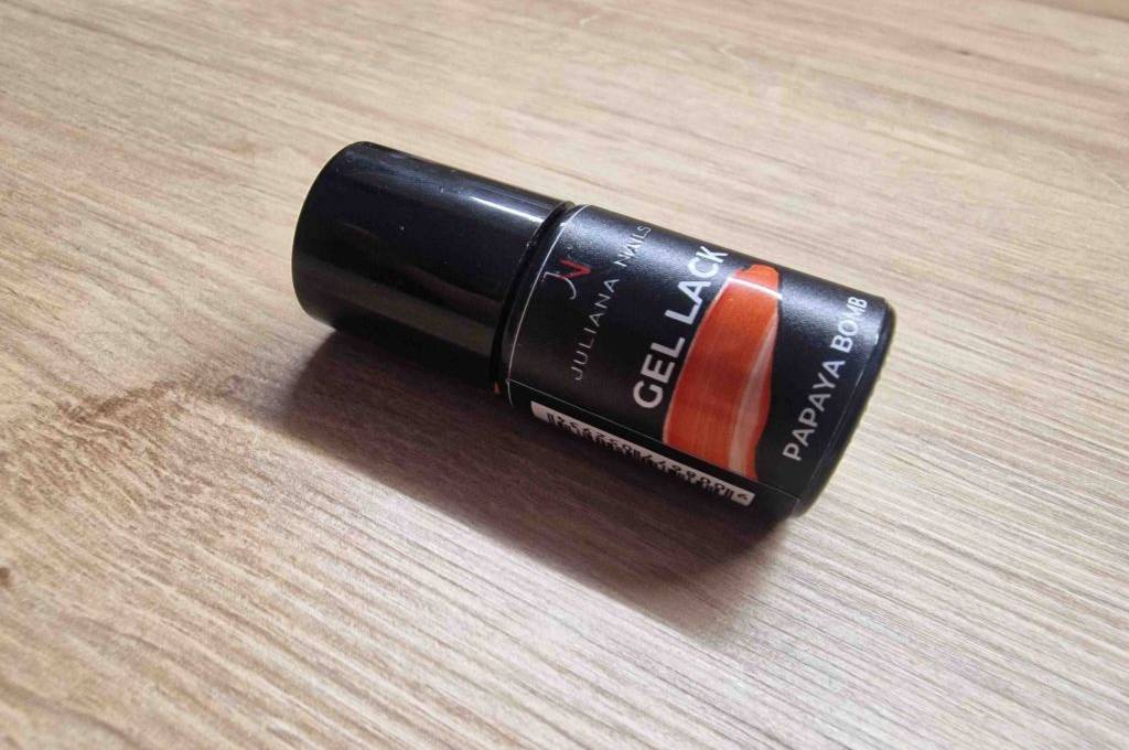 Eine Flasche getesteter Gel-Nagellack liegt quer auf einer Holzfläche.