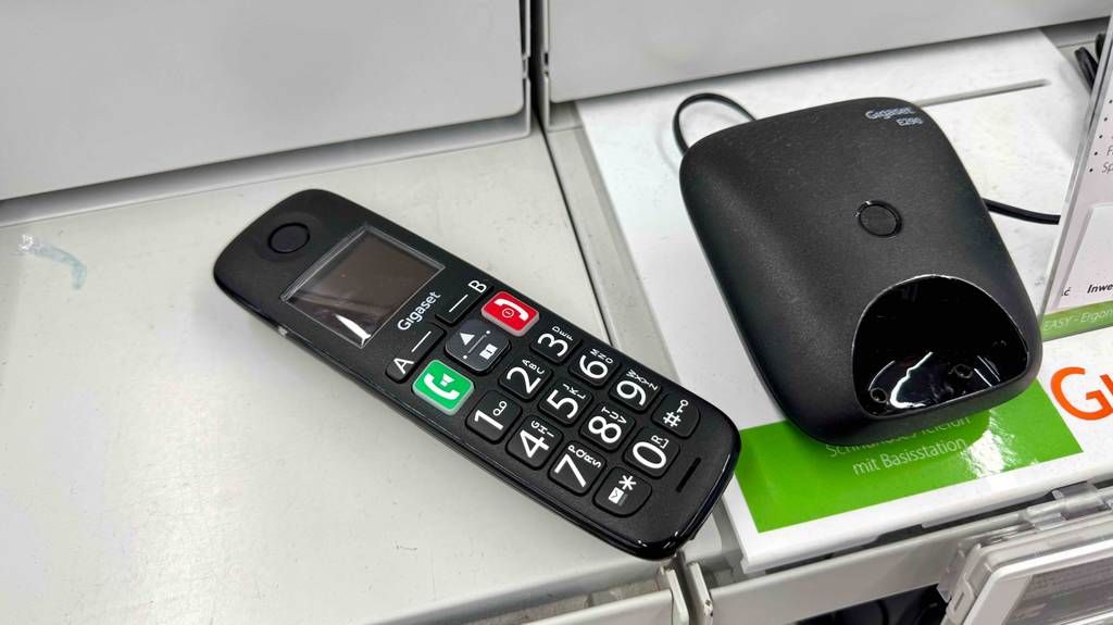 Das getestete Gigaset-Dect-Telefon liegt neben seiner Ladestation auf einem Ausstellungsregal im Verkaufsbereich.