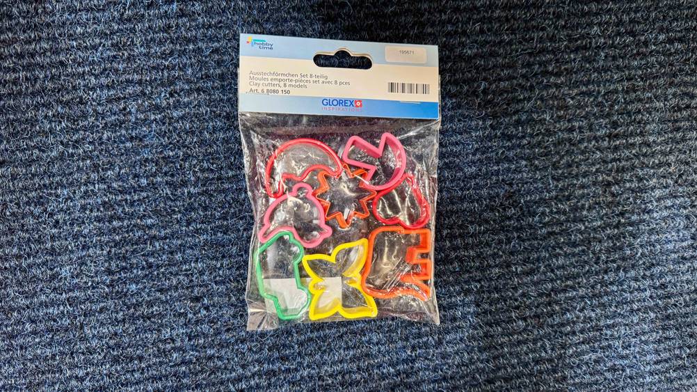Bunte, getestete Ausstechformen liegen in der Verpackung auf einem dunklen Stoff.