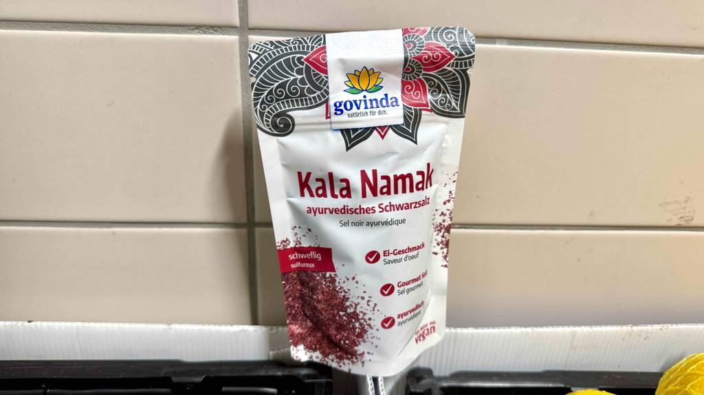 Eine Tüte getestetes Kala-Namak steht vor einer Fliesenwand.