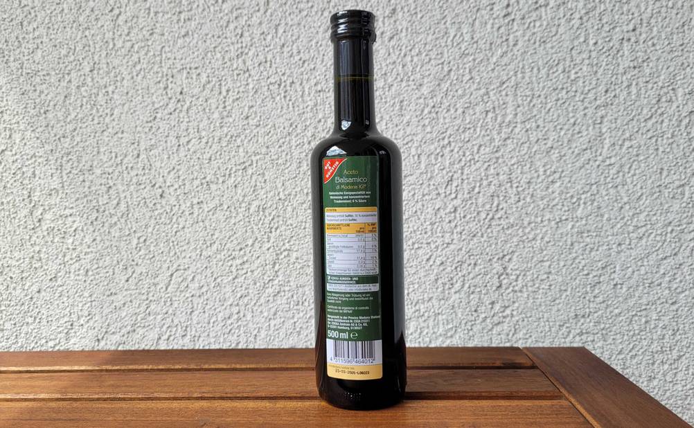 Rückseite einer Flasche des getesteten Balsamico-Essigs vor einer hellen Wand.