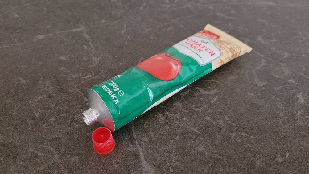 Tomatenmark getestet: Eine geöffnete Tube Tomatenmark auf einer dunklen Fläche.