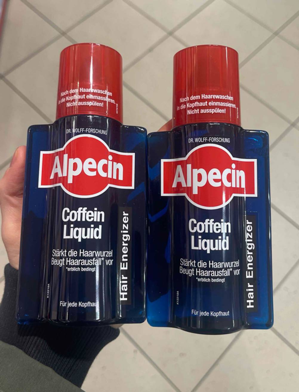 Zwei getestete Haarwachstum-Shampoos für jede Kopfhaut werden nebeneinander in die Kamera gehalten.