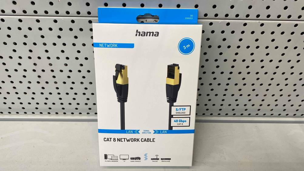 Vor einer hellen Wand auf einer hellen Oberfläche steht eine Packung des getesteten Netzwerkkabels (Cat 8).