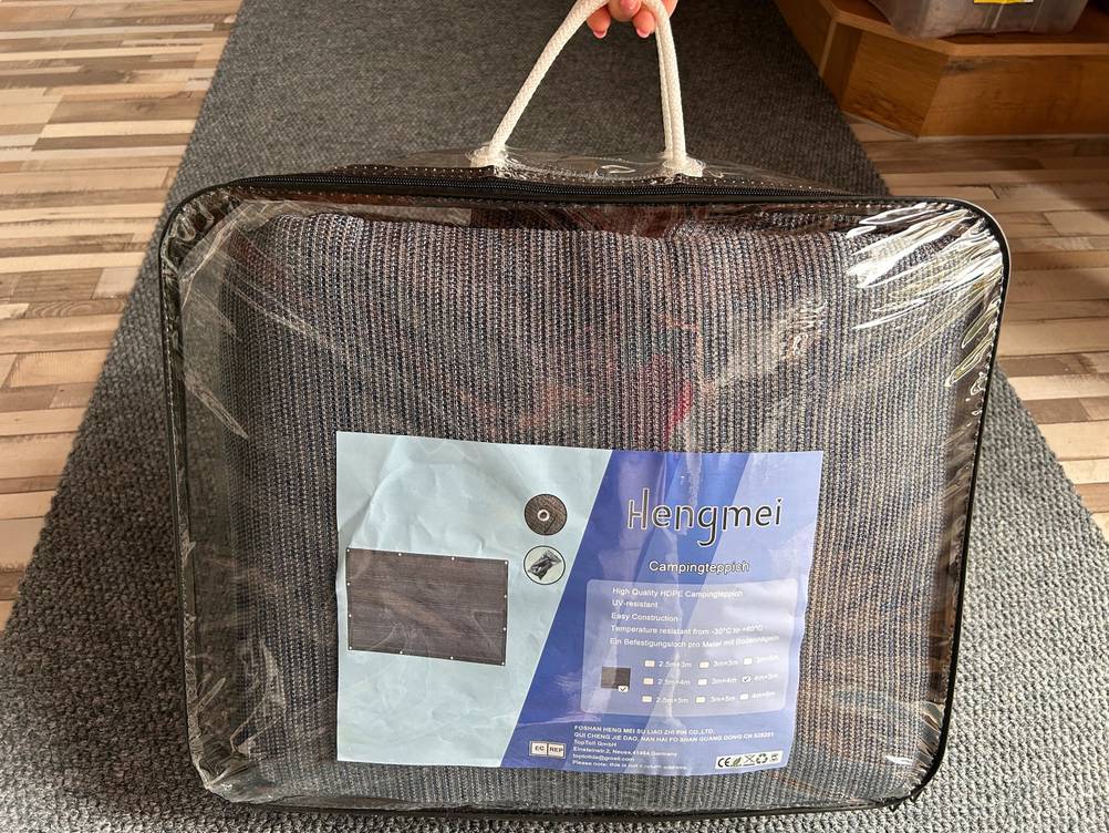 Eine Hand hält den Hänkel einer Tasche in der sich ein getesteter Zeltteppich befindet.