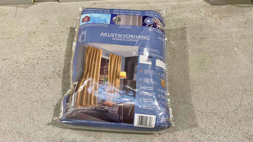 Auf einem grauen Boden liegt ein verpackter Akustikvorhang.