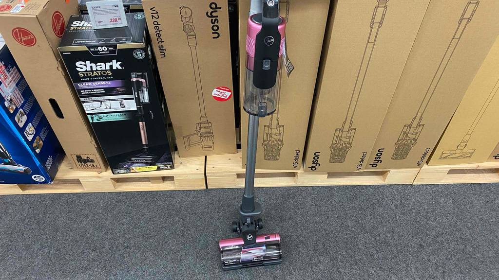 Getesteter Hoover-Staubsauger steht auf dem Boden vor mehreren Verpackungen.