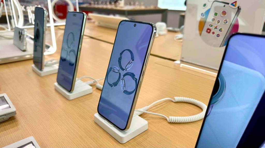 Getestet: Das Smartphone bis 600 Euro steht mit eingeschaltetem Display am Anfang einer Reihe Smartphones auf einem Ausstellungstisch.