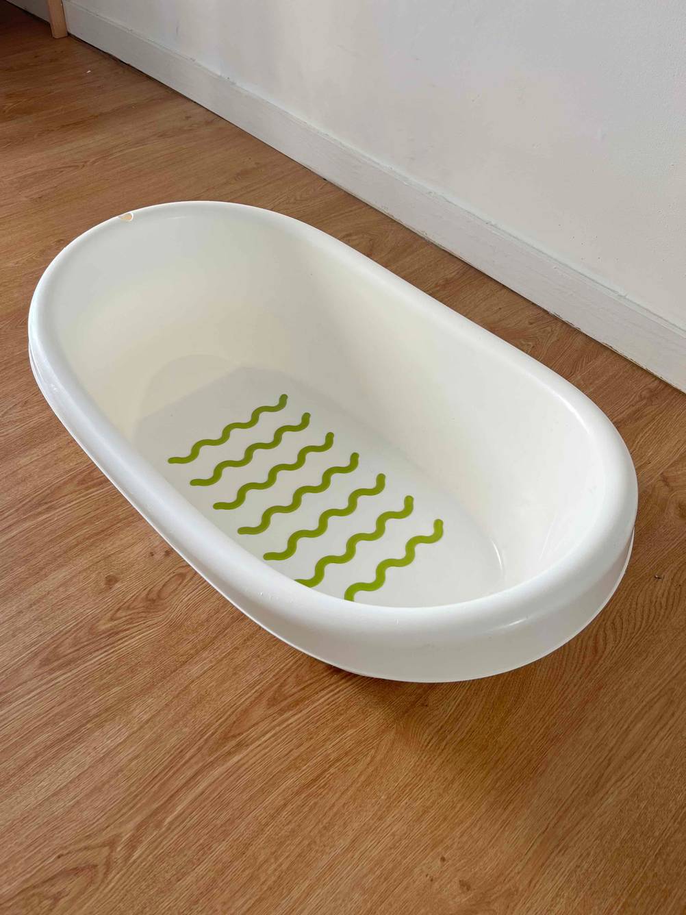 Babybadewanne-Test: Eine weiße Babybadewanne ist auf einem Holzboden platziert.